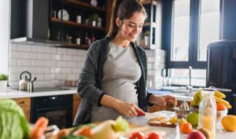 A pregnant woman in the kitchen prepares food for a meal
