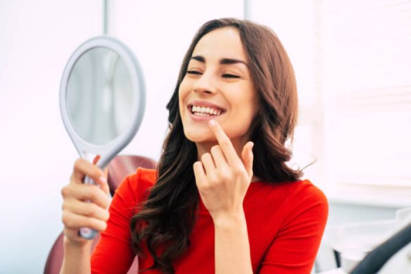 A woman looks at her white teeth in the mirror.