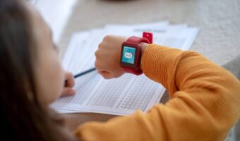 A child in the classroom looks at his smartwatch