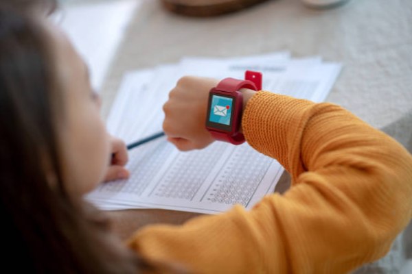 A child in the classroom looks at his smartwatch