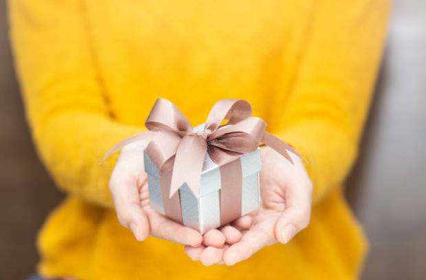 A woman in a yellow sweater gives a gift