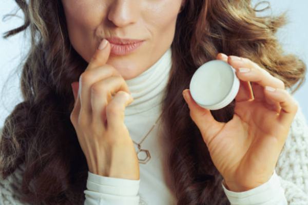 A woman applies balm to dry and chapped lips