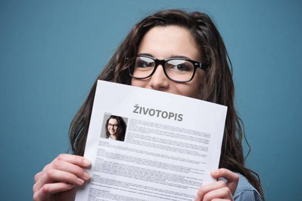 A woman with glasses holds a resume in her hands