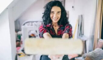 A smiling woman holds a whitewash roller
