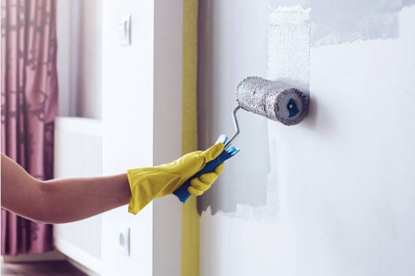 Hand of the person holding the roller and paint the wall