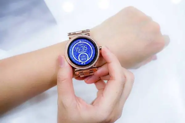 A person's hands and a smartwatch with a blue screen on the wrist